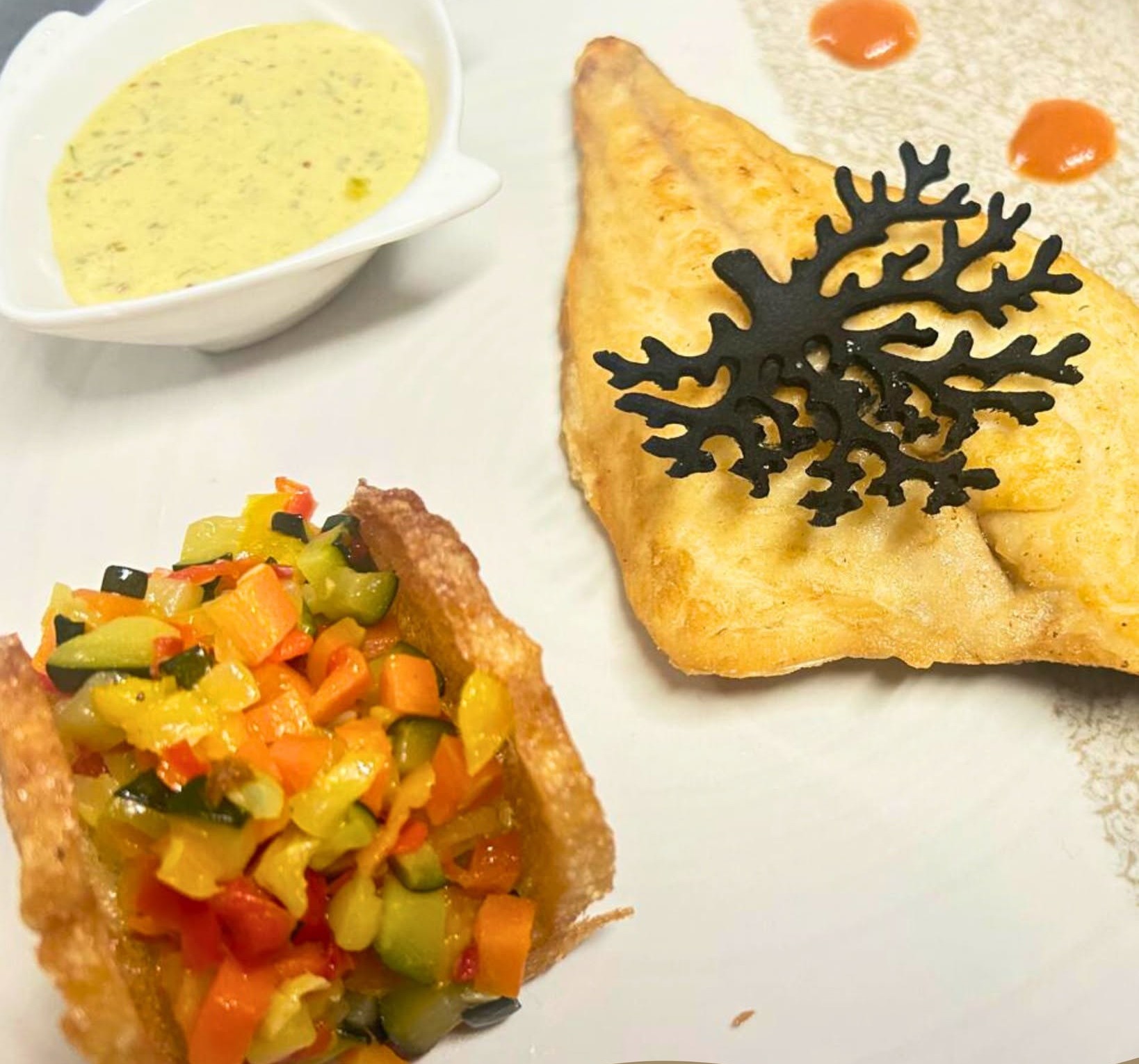 Filetto di pesce dorato con decoro nero a corallo, cestino croccante di verdure a dadini e salsa gialla, piatto Ai Navigli