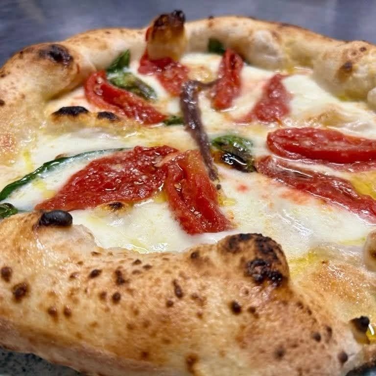Pizza Ai Navigli dal cornicione bruciacchiato con mozzarella fusa, filetti di pomodoro, acciuga, basilico e olio
