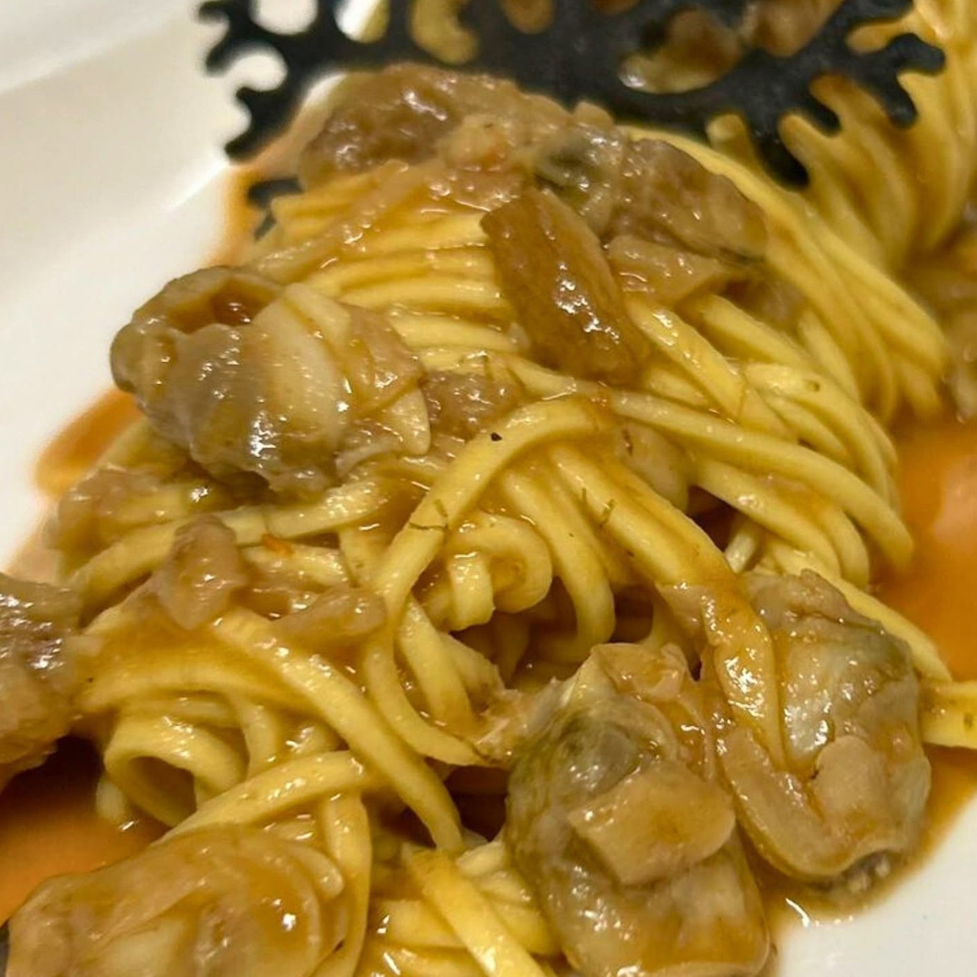Tagliolini all'uovo di Ai Navigli con sugo ambrato e bocconi rosolati, cialda nera decorativa su piatto bianco